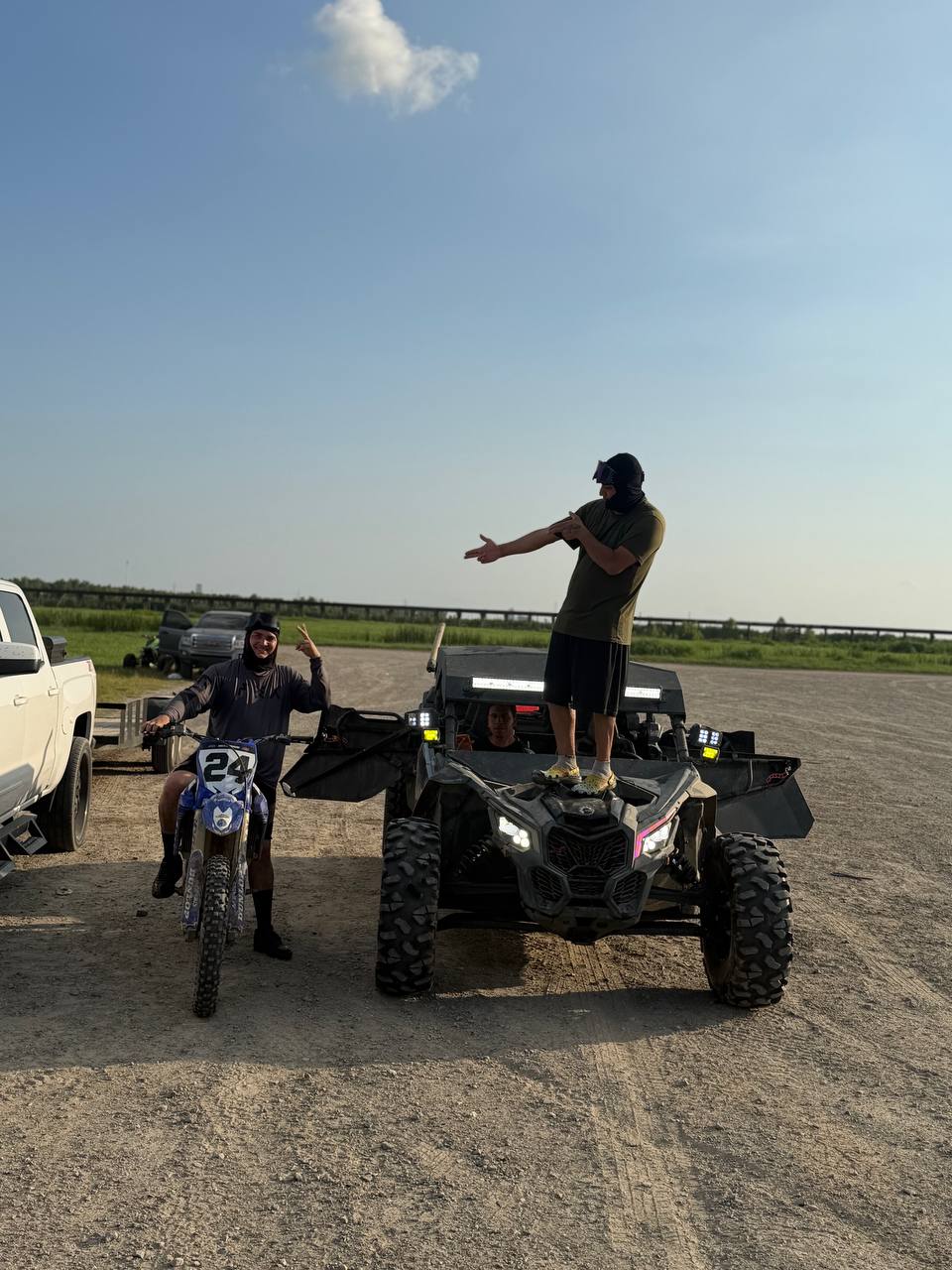 Amigos celebrando junto a la moto y el Can-Am al atardecer